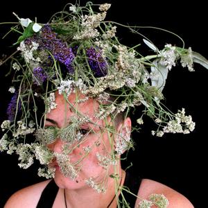 A portrait of Sarah Hudson with their head covered with plants and flowers